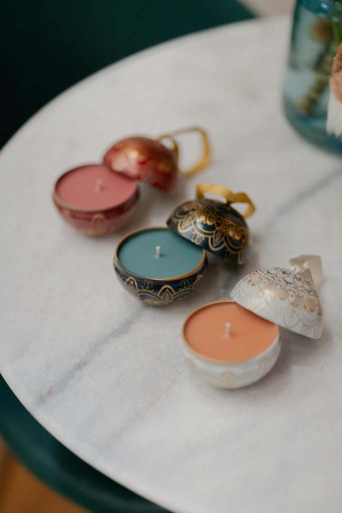 Camila Fernández's 6 Gift Picks for a Heartfelt Holiday - Three candles, color peach, light blue and brick red, inside of cases resembling Christmas ornaments - Photo via Pexels, by  Wolf  Art.